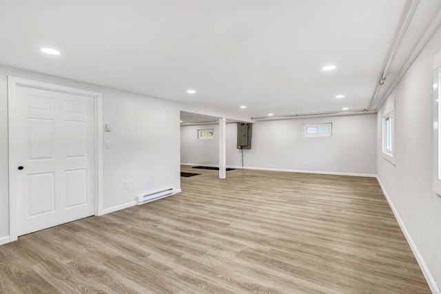 basement featuring electric panel, light hardwood / wood-style floors, and baseboard heating