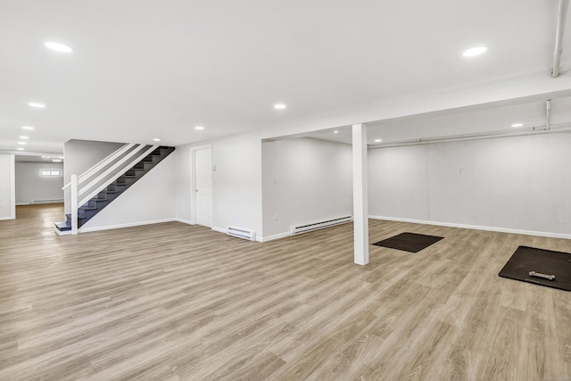 basement featuring baseboard heating and light hardwood / wood-style flooring