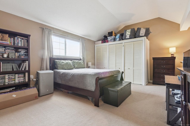 bedroom featuring light colored carpet, lofted ceiling, and a closet