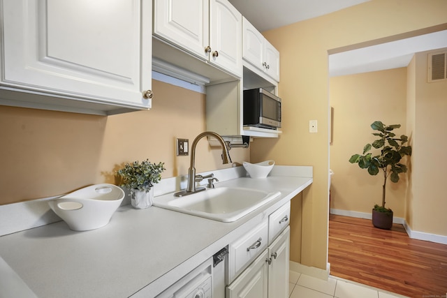 kitchen with light tile patterned floors, white cabinetry, and sink