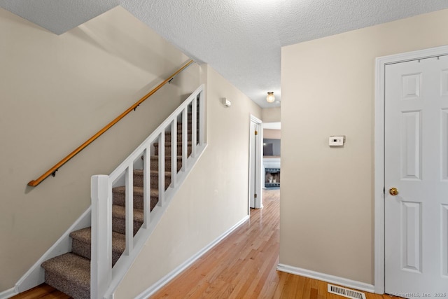 staircase featuring hardwood / wood-style floors and a textured ceiling