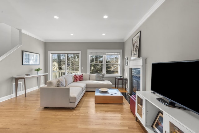 living room with a premium fireplace, ornamental molding, and light hardwood / wood-style flooring