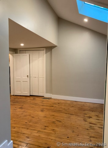 spare room with wood-type flooring and lofted ceiling