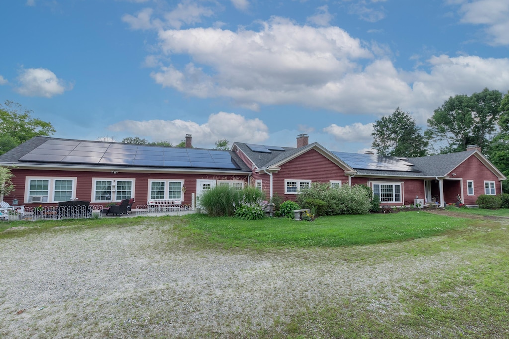 ranch-style house featuring solar panels, a patio area, and a front lawn