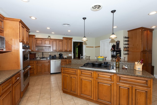 kitchen with dark stone counters, sink, hanging light fixtures, light tile patterned floors, and stainless steel appliances