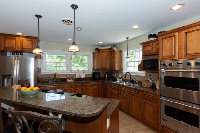 kitchen featuring sink, stainless steel appliances, a kitchen breakfast bar, tasteful backsplash, and pendant lighting