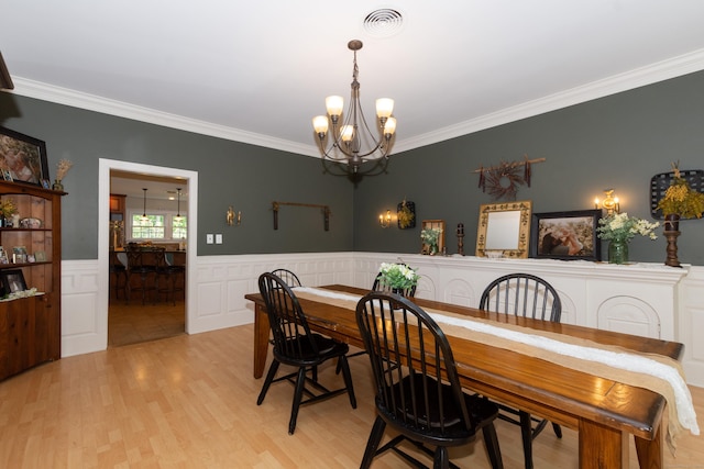 dining space featuring crown molding, light hardwood / wood-style flooring, and a notable chandelier