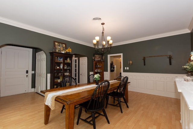 dining space with an inviting chandelier, crown molding, and light hardwood / wood-style flooring