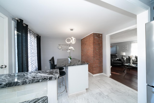 kitchen featuring white cabinetry, kitchen peninsula, dark stone counters, pendant lighting, and a breakfast bar area