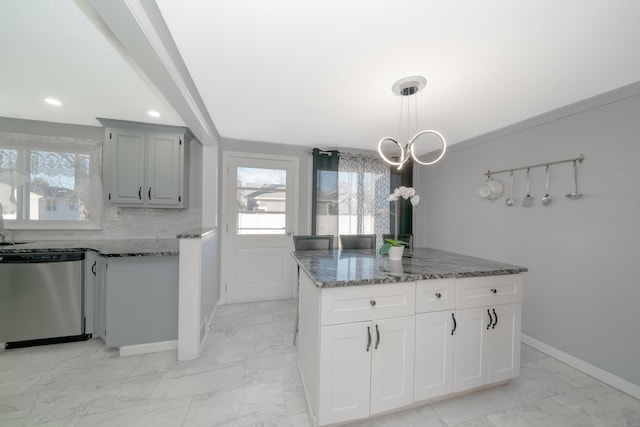 kitchen featuring stainless steel dishwasher, decorative backsplash, dark stone countertops, decorative light fixtures, and a kitchen island