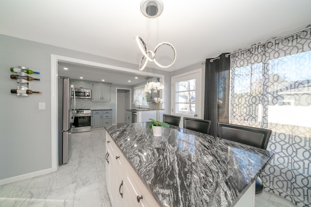 kitchen featuring backsplash, a notable chandelier, a kitchen island, and stainless steel appliances