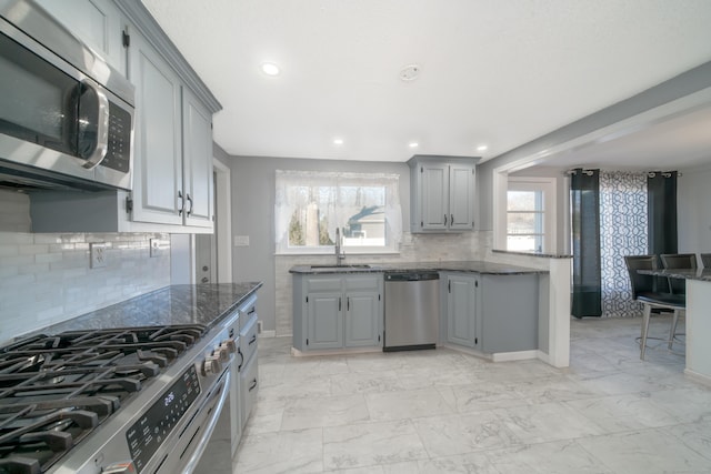 kitchen featuring gray cabinetry, backsplash, sink, and appliances with stainless steel finishes