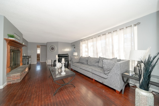 living room with dark hardwood / wood-style floors, a wealth of natural light, and a brick fireplace