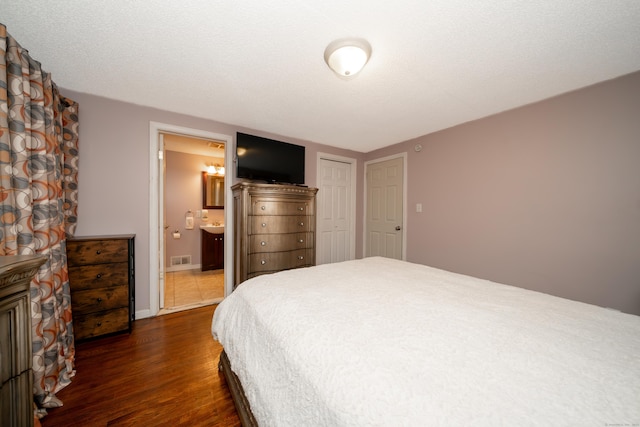 bedroom featuring ensuite bathroom and dark hardwood / wood-style floors