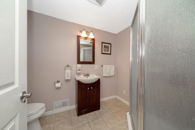 bathroom featuring tile patterned flooring, vanity, toilet, and a shower with door