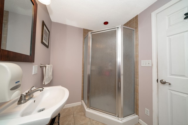 bathroom with tile patterned floors, a textured ceiling, sink, and walk in shower