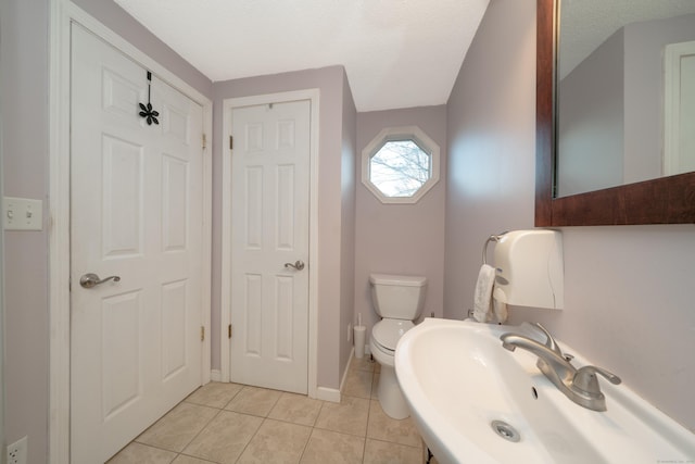 bathroom with tile patterned floors, toilet, sink, and a textured ceiling