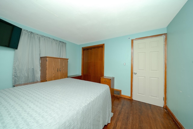 bedroom with dark hardwood / wood-style floors and a closet