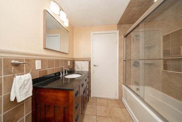 bathroom with vanity, bath / shower combo with glass door, tile patterned flooring, tile walls, and a textured ceiling