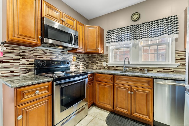 kitchen with decorative backsplash, stainless steel appliances, sink, light tile patterned floors, and stone counters