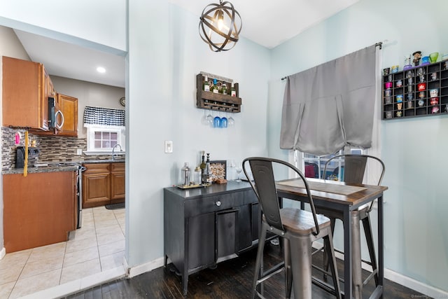 interior space featuring light tile patterned floors, backsplash, stainless steel range with electric cooktop, and sink