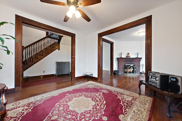 living room with a fireplace, hardwood / wood-style flooring, radiator, and ceiling fan