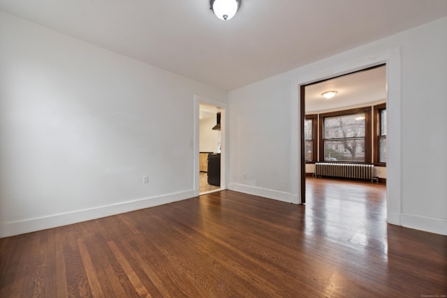 empty room featuring dark hardwood / wood-style flooring and radiator heating unit