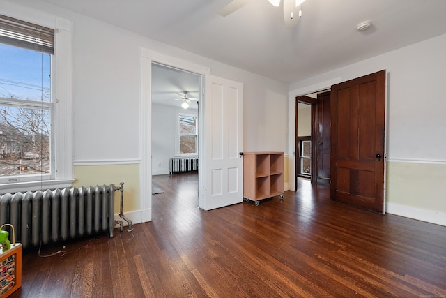 spare room with radiator heating unit, dark hardwood / wood-style floors, and ceiling fan