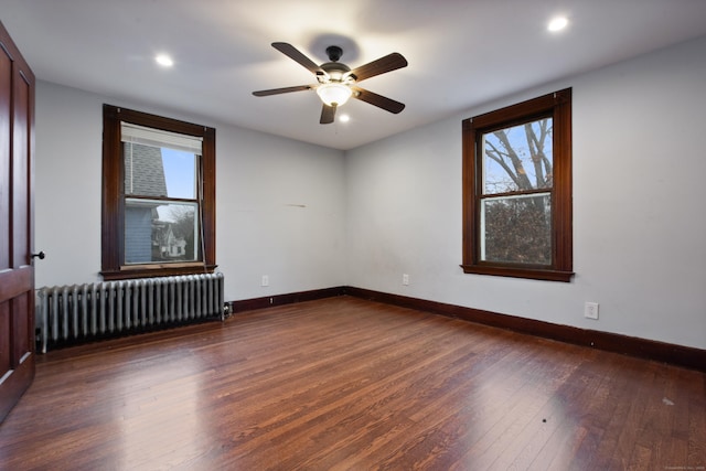 unfurnished room featuring dark hardwood / wood-style floors, radiator, and ceiling fan