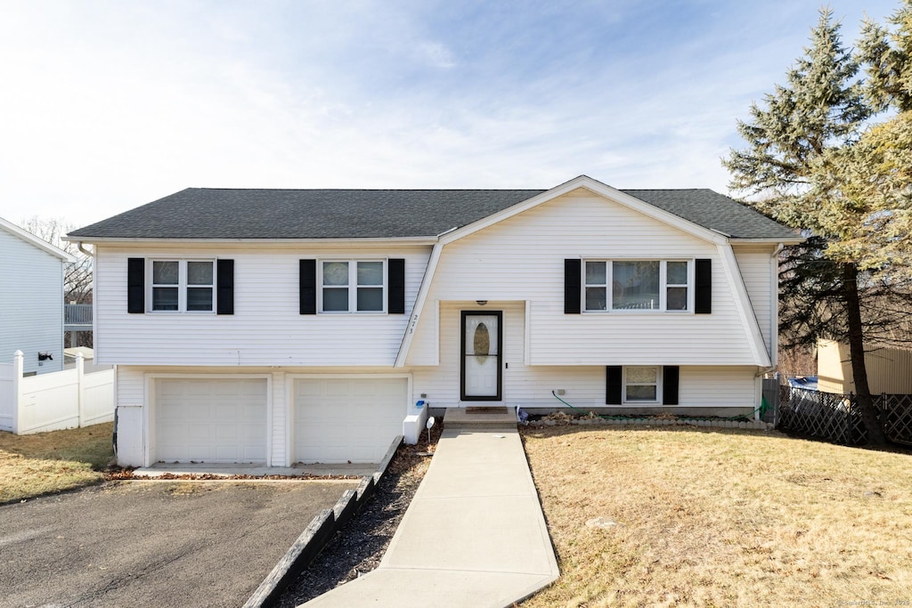 raised ranch featuring a front yard and a garage