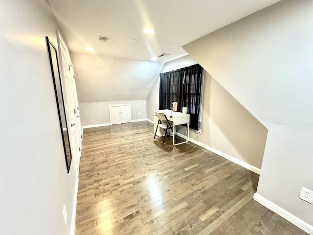 additional living space with hardwood / wood-style floors and lofted ceiling