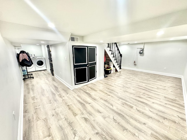 basement featuring washing machine and clothes dryer and light wood-type flooring