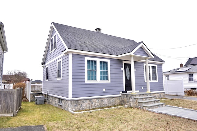 view of front of house with central AC and a front yard