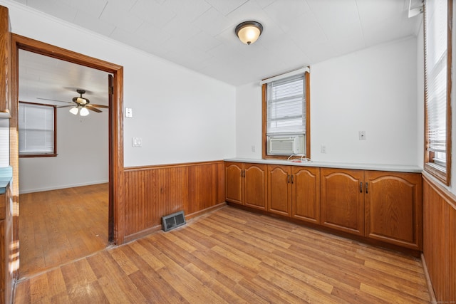 empty room with ornamental molding, light hardwood / wood-style flooring, cooling unit, and a healthy amount of sunlight