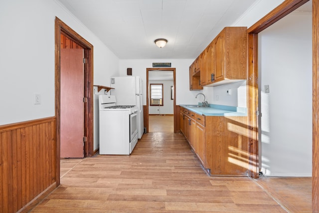 kitchen featuring wood walls, crown molding, sink, gas range gas stove, and light hardwood / wood-style floors