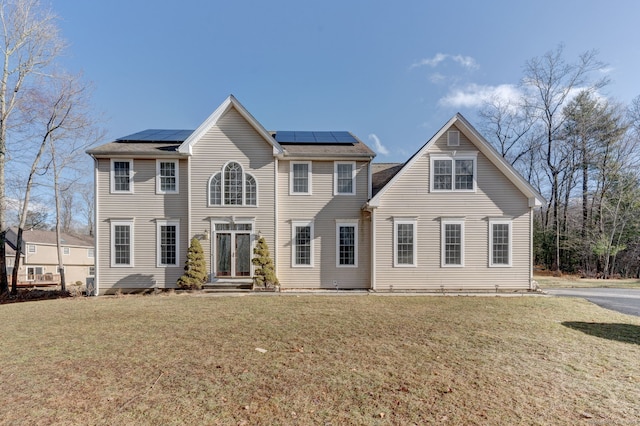 colonial inspired home with solar panels and a front yard