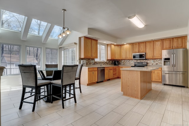 kitchen with a wealth of natural light, stainless steel appliances, decorative light fixtures, decorative backsplash, and a kitchen island