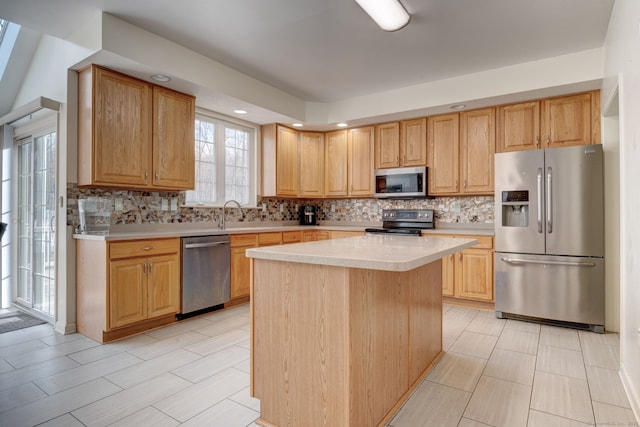 kitchen with appliances with stainless steel finishes, backsplash, a kitchen island, and light brown cabinetry