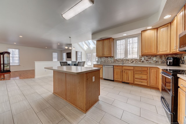 kitchen with a center island, sink, decorative backsplash, appliances with stainless steel finishes, and decorative light fixtures