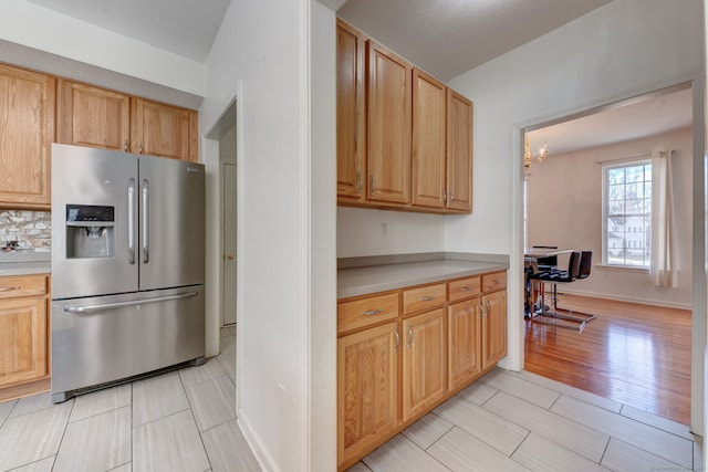 kitchen featuring tasteful backsplash, light brown cabinetry, a chandelier, and stainless steel refrigerator with ice dispenser