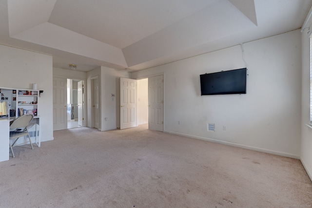 interior space with light colored carpet and a raised ceiling