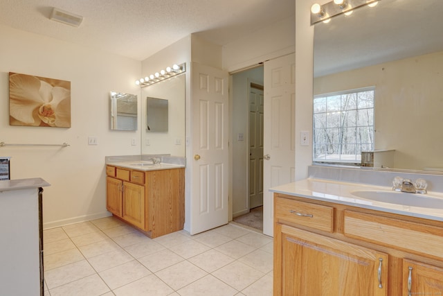 bathroom with tile patterned floors, vanity, and a textured ceiling