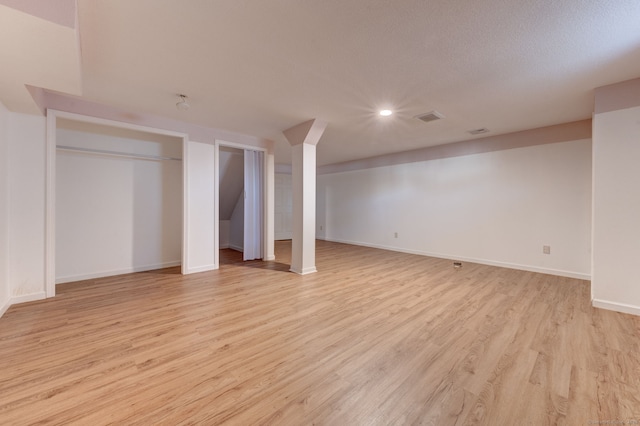 basement with light wood-type flooring and a textured ceiling