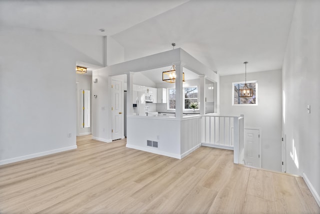 unfurnished living room with lofted ceiling, light hardwood / wood-style flooring, and a notable chandelier