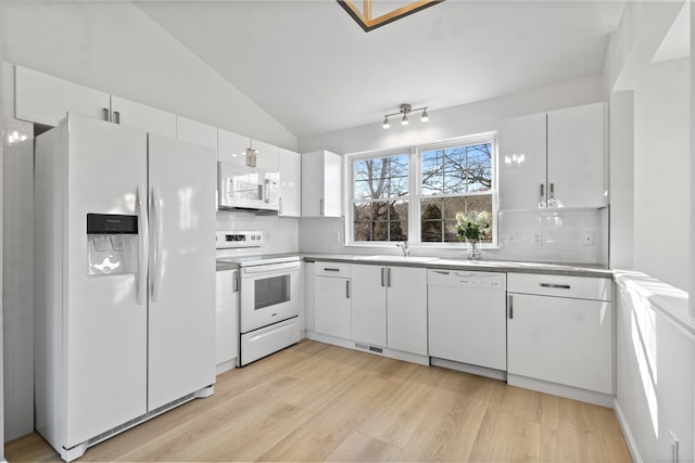 kitchen featuring white cabinetry, backsplash, white appliances, vaulted ceiling, and sink