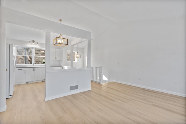 unfurnished room featuring vaulted ceiling, light hardwood / wood-style flooring, and an inviting chandelier