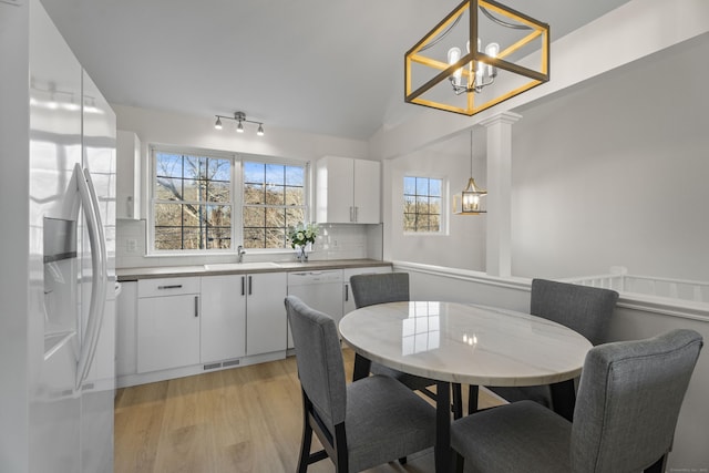 dining area featuring lofted ceiling, a notable chandelier, sink, and light hardwood / wood-style floors