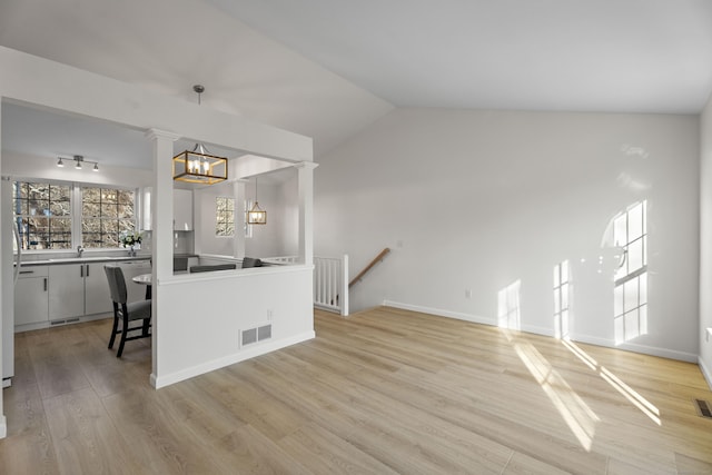 kitchen featuring decorative light fixtures, lofted ceiling, a chandelier, and light hardwood / wood-style flooring