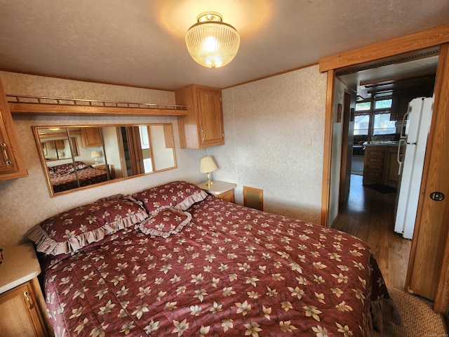 bedroom featuring white fridge, dark wood-type flooring, and a textured ceiling