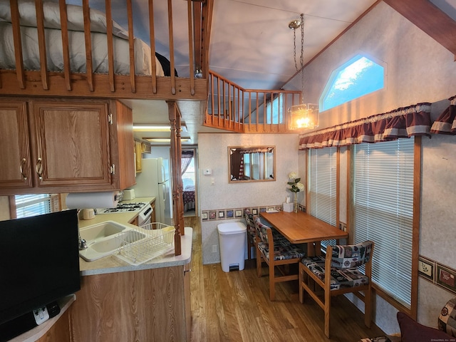 kitchen featuring sink, hanging light fixtures, light hardwood / wood-style flooring, white refrigerator, and lofted ceiling